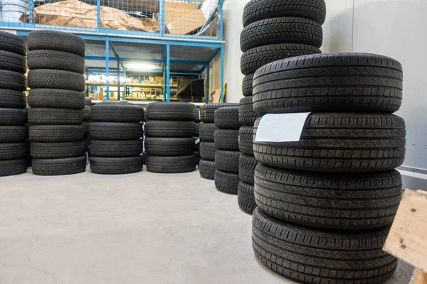 En un garaje, se apilan muchos neumáticos nuevos para que puedan instalarse —  Fotos de Stock