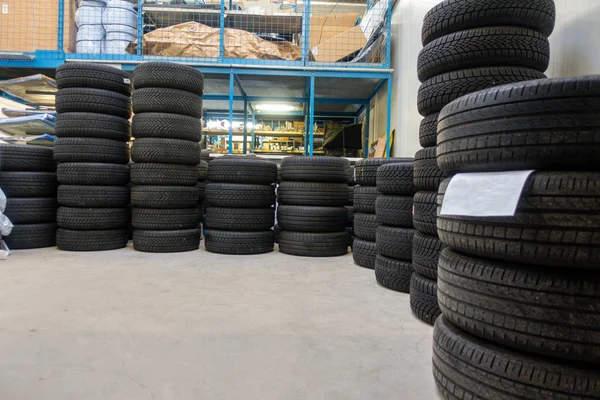 En un garaje, se apilan muchos neumáticos nuevos para que puedan instalarse —  Fotos de Stock