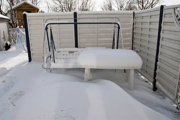 Una gruesa manta blanca de nieve cubre muebles de jardín de pie o — Foto de Stock
