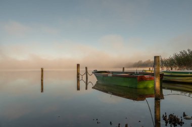 Gölde bazı kayıklar demirli ve gölde sis var. 