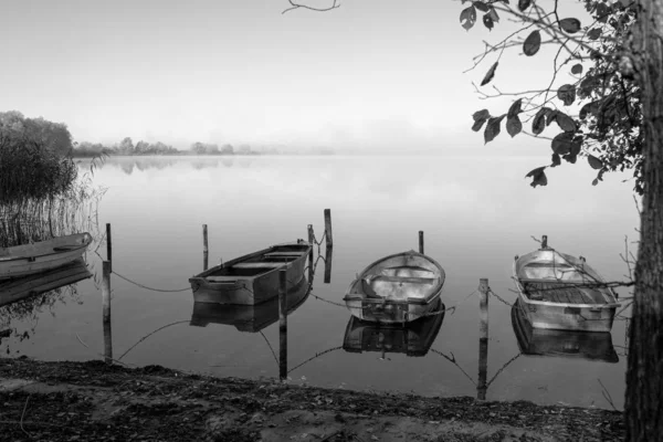 En un lago algunos botes de remos están amarrados y en el lago hay niebla — Foto de Stock