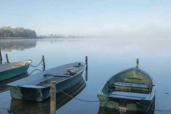 На озере пришвартованы лодки, а на озере туман. — стоковое фото