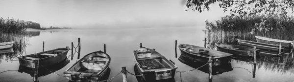 En un lago algunos botes de remos están amarrados y en el lago hay niebla — Foto de Stock