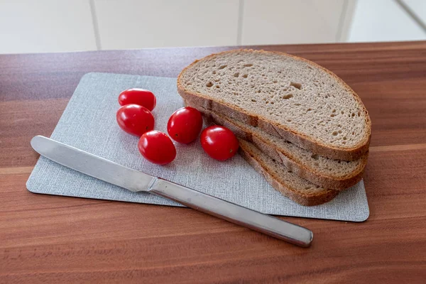 早餐板上放着小西红柿 三片面包和一把小刀 — 图库照片