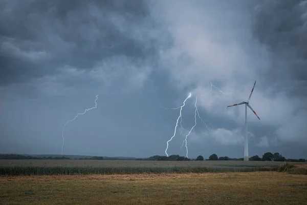 lightning strikes the ground next to a wind turbine