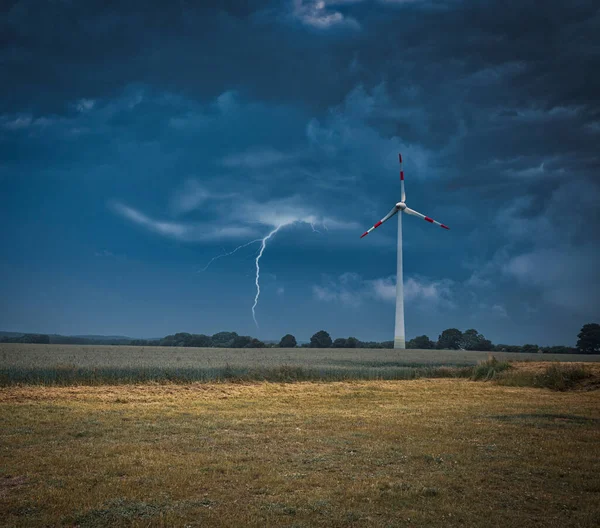 lightning strikes the ground next to a wind turbine