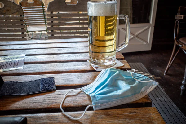 Uma Máscara Facial Fica Lado Copo Cerveja Restaurante — Fotografia de Stock