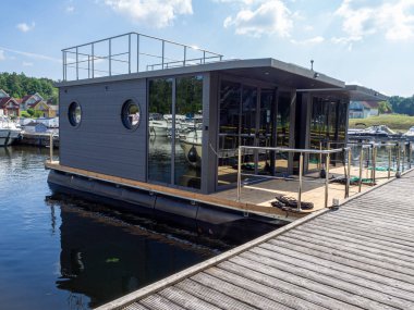 Bir limanda iki yüzen ev iskeleye yan yana demirlenmiş.