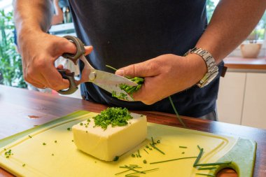 a man uses kitchen scissors to make herb butter clipart