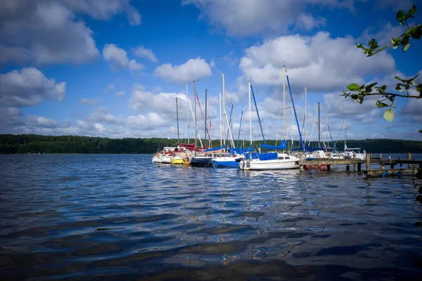 在一个湖上 许多帆船靠岸在一个登陆台上 蓝蓝的天空布满了白云 — 图库照片