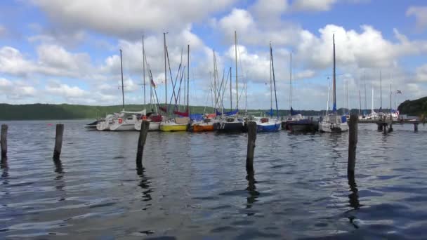 湖では多くの帆船が着陸時に横に係留され白い雲と空は青い — ストック動画