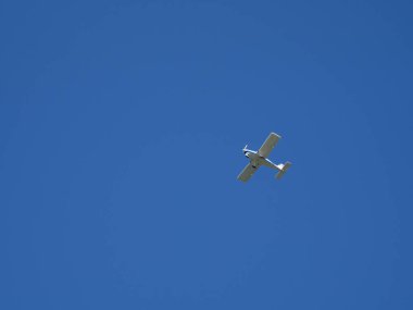 Bulutsuz mavi gökyüzünde küçük beyaz bir uçak uçuyor.