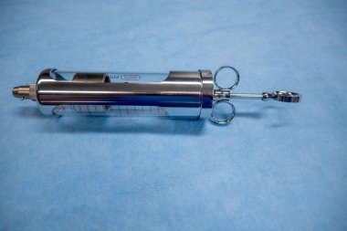 Bir araya getirilmiş idrar kesesi şırıngası mavi cerrahi tabanında yatıyor.