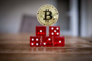 Altın bir Bitcoin para kırmızı zarların üzerinde duruyor.
