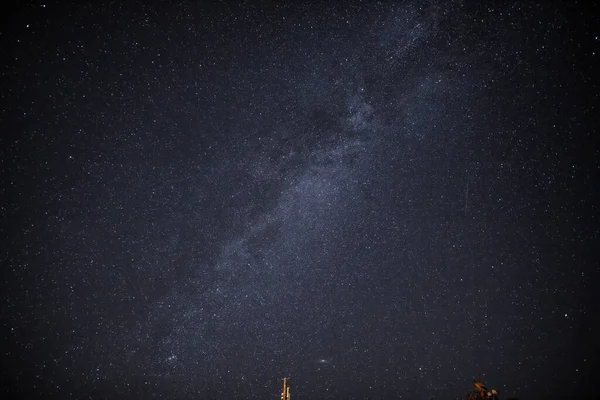 in the night sky you can see the milky way and the traces of satellites