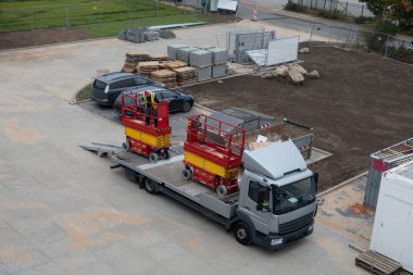 İki kırmızı kaldırma platformu nakledilmek üzere bir kamyona yüklenir.