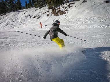 Bir çocuk güneşli havada ve mavi gökyüzünde kayak yapıyor.