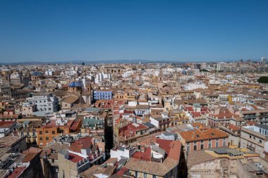 Valencia, İspanya 'nın havadan panoramik manzarası, geleneksel Akdeniz mimarisi, renkli çatıları ve berrak mavi gökyüzü altında ikonik mavi kubbeli kiliseleriyle tarihi eski kasabayı gösteriyor. Canlı şehir manzarası benzersiz bir manzarayı vurguluyor.