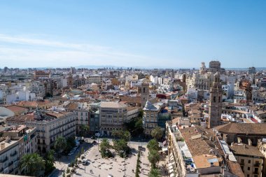 Valencia, İspanya 'nın havadan panoramik manzarası, geleneksel Akdeniz mimarisi, renkli çatıları ve berrak mavi gökyüzü altında ikonik mavi kubbeli kiliseleriyle tarihi eski kasabayı gösteriyor. Canlı şehir manzarası benzersiz bir manzarayı vurguluyor.