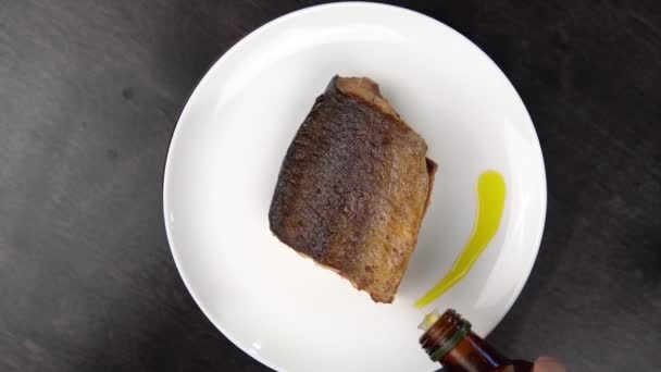 Piece of fried red fish on white plate rotates against black table. — Stock Footage Piece of fried red fish on white plate rotates against black table. Royalty Free Stock Footage