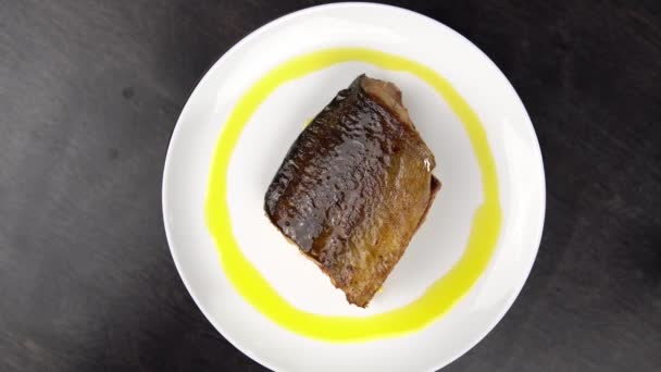 Piece of fried red fish on white plate rotates against black table. — Stock Footage Piece of fried red fish on white plate rotates against black table. Video Clip