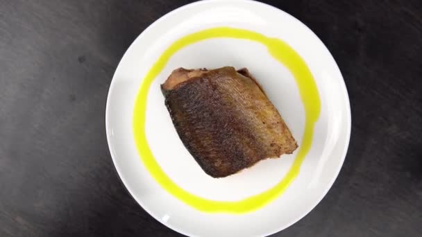 Piece of fried red fish on white plate rotates against black table. — Stock Footage Piece of fried red fish on white plate rotates against black table. Video Clip
