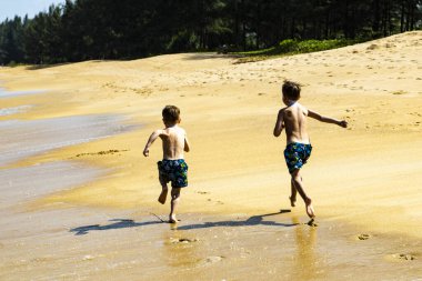 Kumsalda koşan iki çocuk.