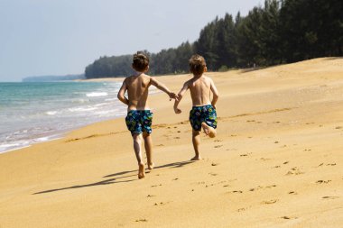 Kumsalda koşan iki çocuk.