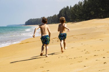 Kumsalda koşan iki çocuk.