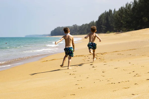 Kumsalda koşan iki çocuk.