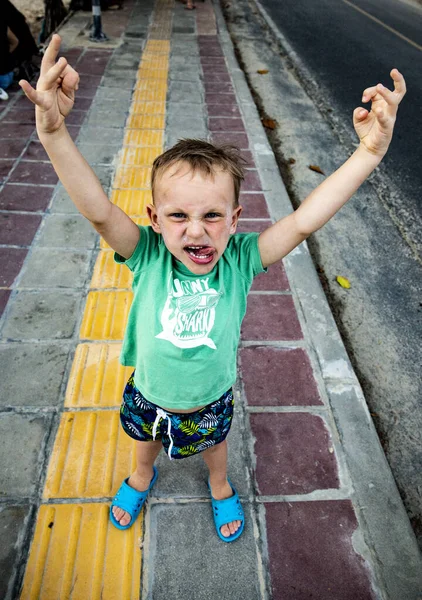 Chłopiec wyciąga język i podnosi ręce. — Zdjęcie stockowe