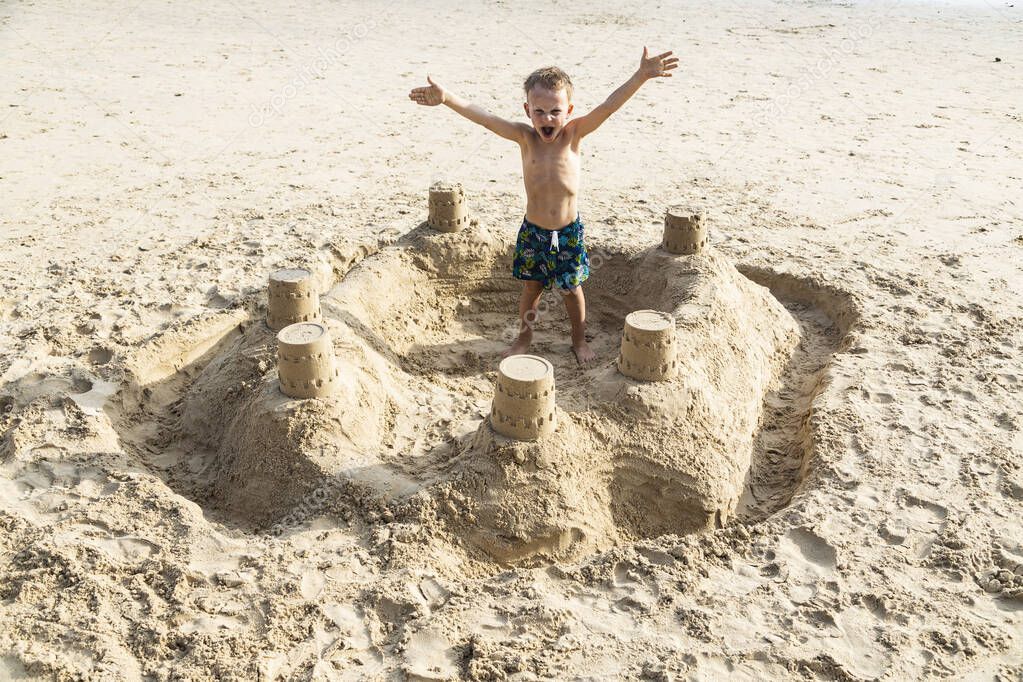 a boy stands in a sand castle