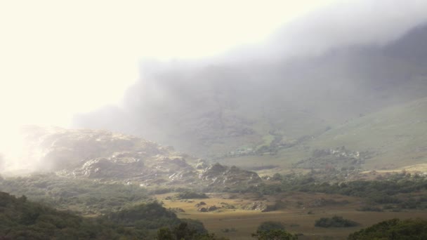Световые лучи пронизывают облака и туман и сияют на скалах в долине — стоковое видео