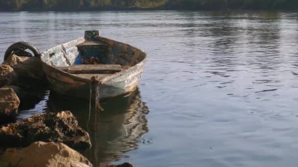 Oude afgemeerd boot in een rivier, met bomen aan de andere kant — Stockvideo