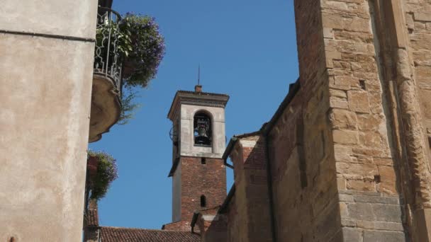 Bell tower mellan en blomstrande balkong och antika vägg i Pavia, Italien — Stockvideo