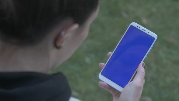 Женщина дважды поворачивается и пялится на синий экран телефона — стоковое видео