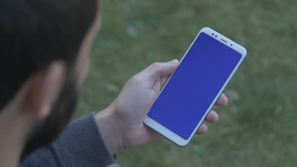 Zurdo hombre tocando en el teléfono de pantalla azul — Vídeos de Stock