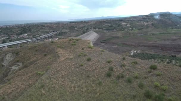 Colpo aereo sopra una collina con una strada sullo sfondo — Video Stock