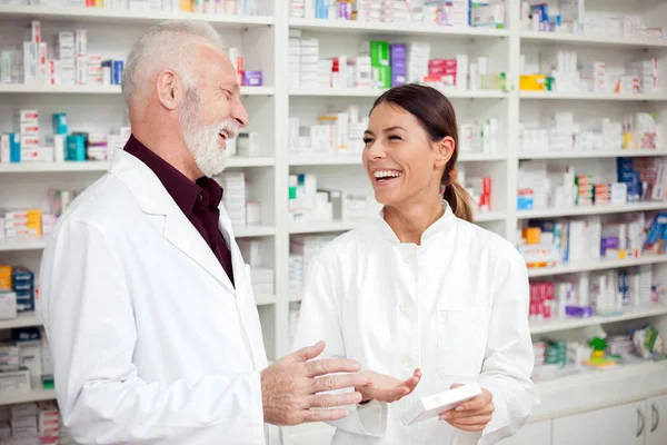 Medicine, pharmaceutics, health care and people concept - Young female and senior male pharmacists discussing about medications.