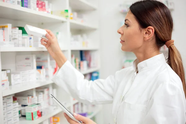 Hermoso Joven Farmacéutico Tomando Caja Medicamentos Estantería —  Fotos de Stock