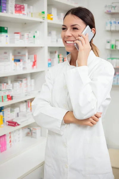 Beautiful young pharmacist talking with patient over the phone