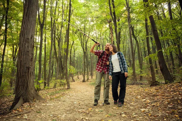 Genç iki kareli gömlek orman içinden güzel bir sonbahar gününde hiking içinde gülümseyen. Adam bir mesafe yürüyüş kutup için işaret ediyor