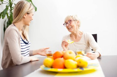Kıdemli anne ve kızı konuşuyor ve parlak çay içme yemek odası yaktı