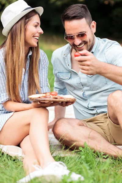 Hermosa pareja joven feliz disfrutando de su tiempo juntos, teniendo un picnic relajante en un parque — Foto de Stock