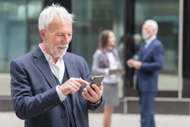 Mutlu kıdemli işadamı internette gezinme veya akıllı telefonda mesajlaşma