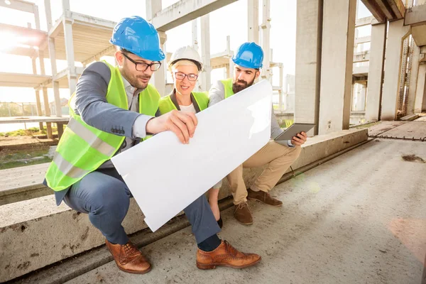 Equipo de jóvenes arquitectos exitosos mirando planos de planta durante una reunión — Foto de Stock