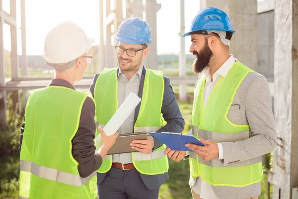 Pequeño grupo de arquitectos discutiendo detalles del proyecto y comprobando el progreso del trabajo — Foto de Stock