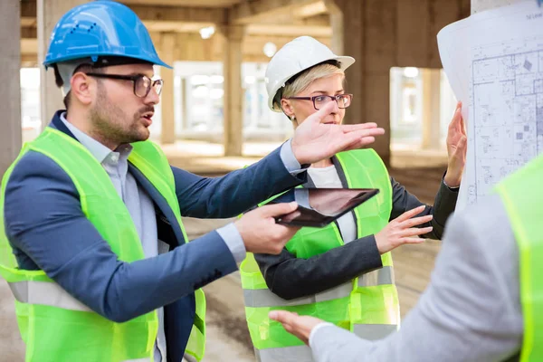 Equipo de jóvenes arquitectos discutiendo y discutiendo durante una reunión en un sitio de construcción — Foto de Stock