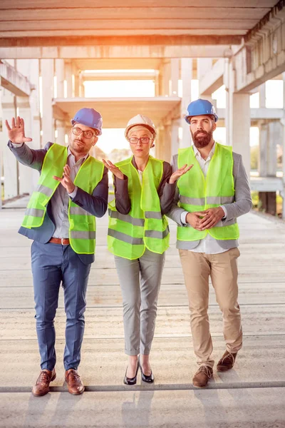 Groupe mixte d'architectes marchant sur le chantier de construction en béton préfabriqué, inspectant l'avancement des travaux — Photo