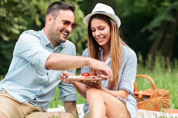 Sonriendo feliz joven pareja disfrutando de su tiempo en un parque, teniendo un picnic romántico casual — Foto de Stock